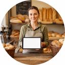Mitarbeiterin einer Landbäckerei an der Verkaufstheke mit Tablet und Bestellübersicht