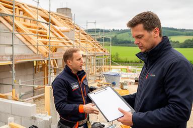 Bauleiter prüft Kostenplan auf einer Baustelle im ländlichen Nordrhein-Westfalen